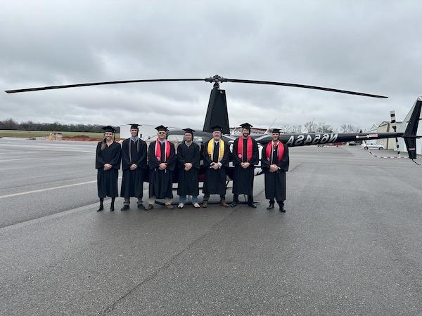 航空科学 graduates infront of one of a helicopter
