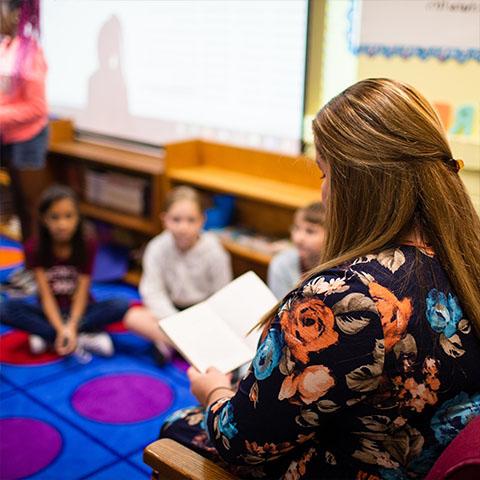 Student reads to kids in a classroom